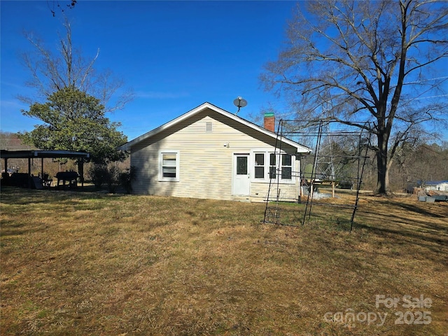 rear view of property with a chimney and a lawn