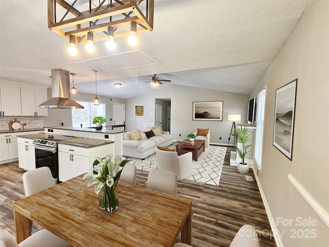 dining space with vaulted ceiling, a textured ceiling, wood finished floors, and attic access