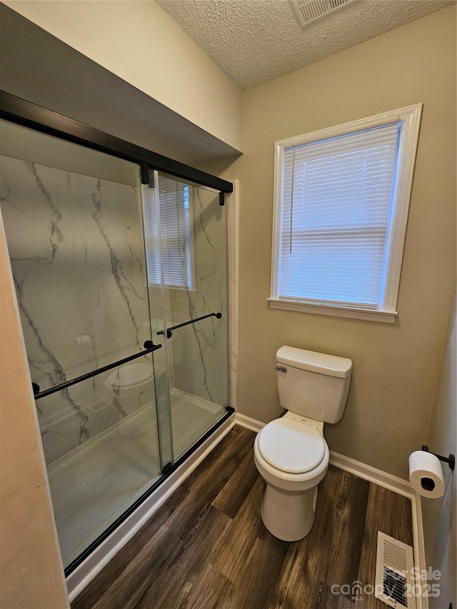 full bath featuring toilet, a marble finish shower, visible vents, and wood finished floors