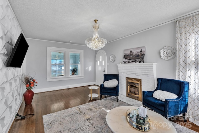 living area with a fireplace, an inviting chandelier, wood finished floors, and a textured ceiling