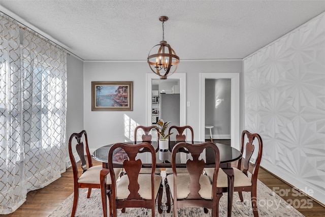 dining room featuring a notable chandelier, wood finished floors, and a textured ceiling