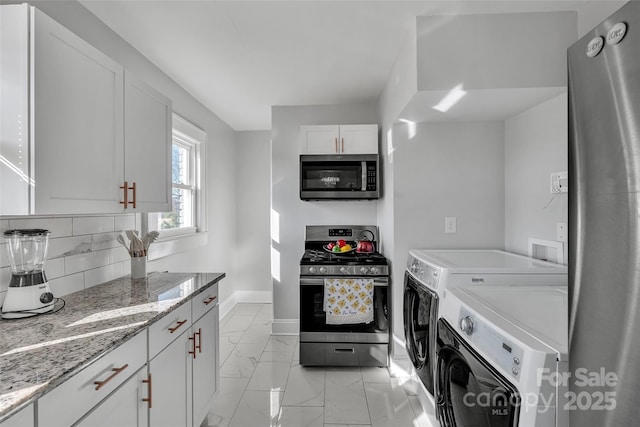 kitchen featuring independent washer and dryer, marble finish floor, backsplash, appliances with stainless steel finishes, and baseboards