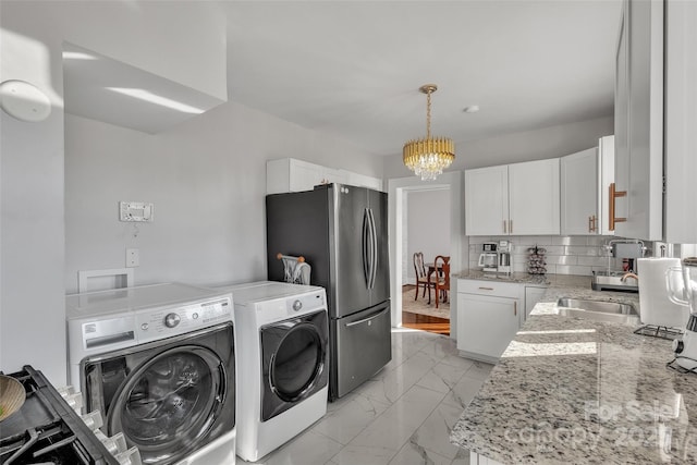 kitchen with light stone countertops, washer and clothes dryer, marble finish floor, backsplash, and a chandelier