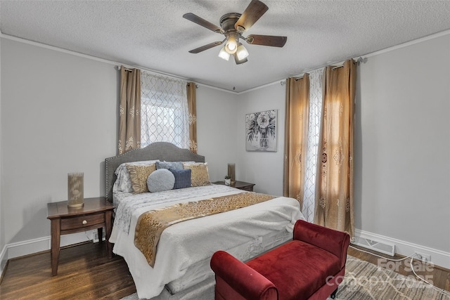 bedroom featuring a ceiling fan, baseboards, wood finished floors, visible vents, and a textured ceiling