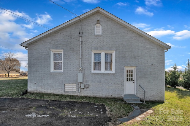 back of property featuring a yard and brick siding