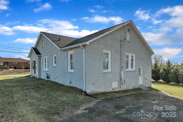 view of side of property with entry steps, a lawn, brick siding, and crawl space