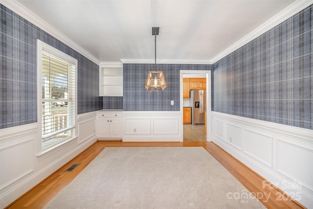 unfurnished dining area with light wood-style floors, visible vents, and wallpapered walls