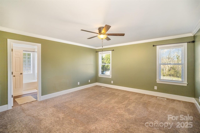 carpeted spare room featuring ornamental molding, a ceiling fan, and baseboards