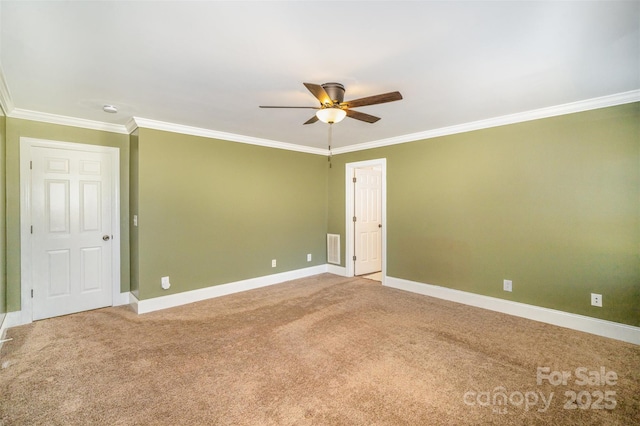 carpeted spare room with visible vents, crown molding, baseboards, and ceiling fan