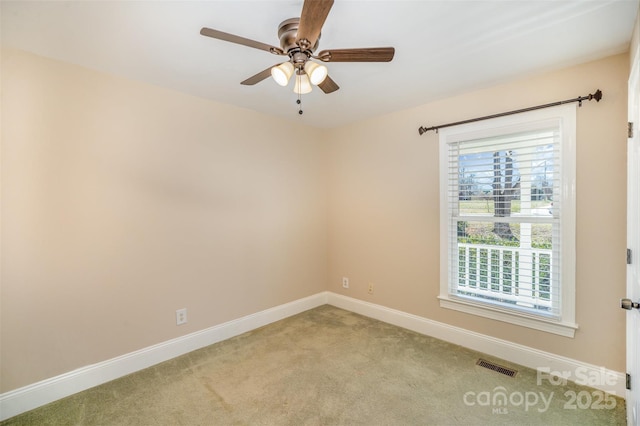 spare room with light colored carpet, visible vents, ceiling fan, and baseboards