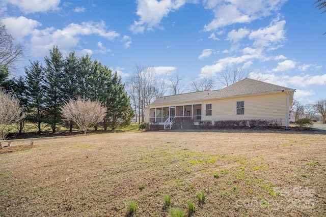 rear view of house featuring a sunroom and a yard