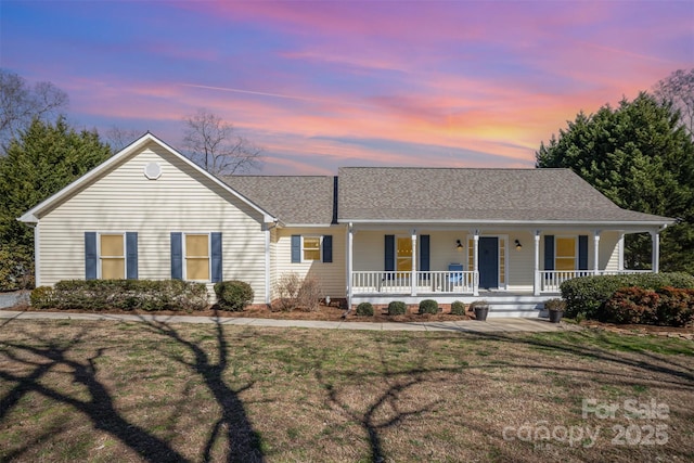 single story home featuring a shingled roof, covered porch, and a lawn