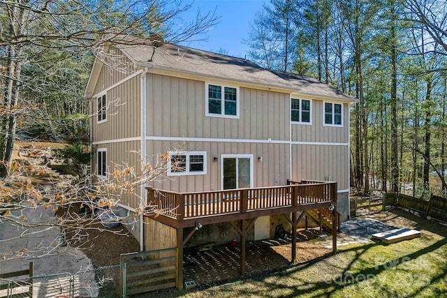 back of house with a shingled roof, fence, and a deck