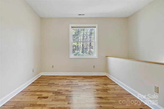 spare room featuring light wood-style floors, baseboards, and visible vents