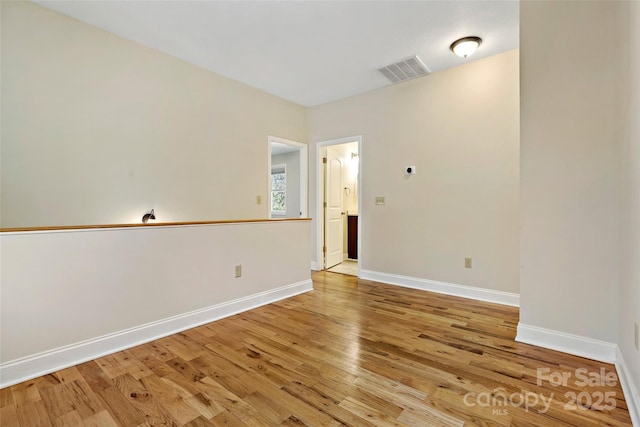 spare room with light wood-style flooring, visible vents, and baseboards