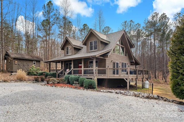 rustic home with a shed, a porch, a shingled roof, and an outbuilding