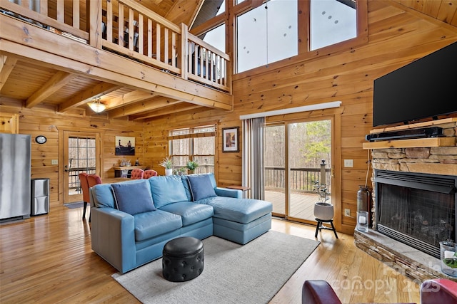 living room featuring light wood finished floors, wooden walls, lofted ceiling with beams, wooden ceiling, and a fireplace