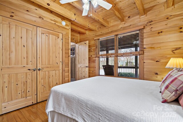 bedroom with wood walls, wood ceiling, beam ceiling, and wood finished floors