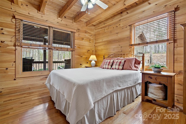 bedroom with light wood-type flooring, wooden ceiling, wooden walls, and beamed ceiling