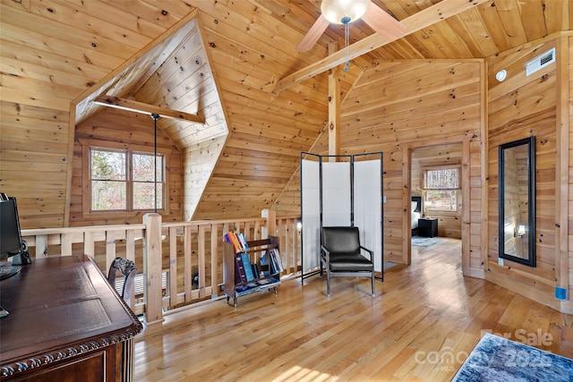 interior space with a wealth of natural light, light wood-style flooring, and wooden walls