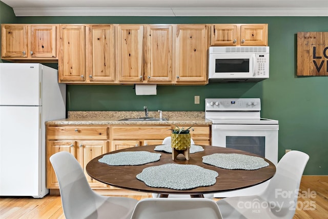 kitchen featuring white appliances, a sink, light countertops, ornamental molding, and light brown cabinetry