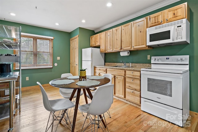 kitchen with white appliances, light countertops, light brown cabinetry, light wood-type flooring, and a sink