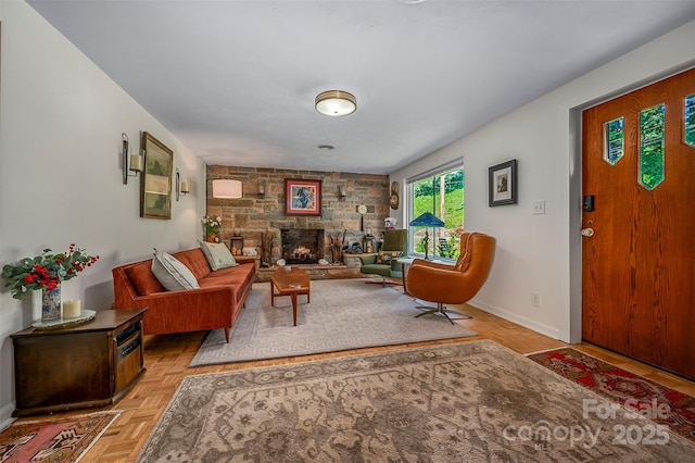 living room featuring a stone fireplace and baseboards