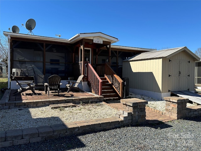 back of property featuring a storage shed, a patio, and an outbuilding