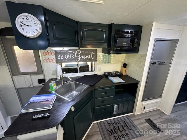 kitchen with dark countertops, dark cabinets, visible vents, and a sink