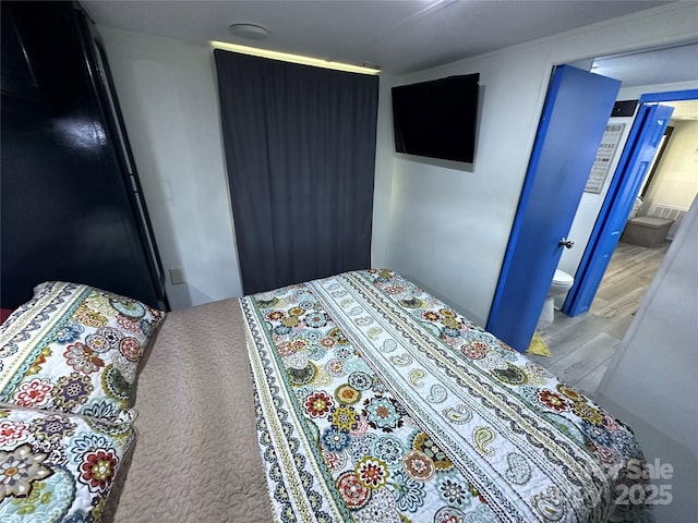 bedroom featuring light wood-type flooring and ensuite bath