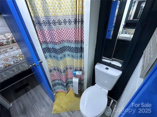 full bathroom with toilet, a sink, and wood finished floors