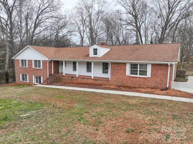 ranch-style home featuring a front yard, a porch, a shingled roof, a chimney, and brick siding