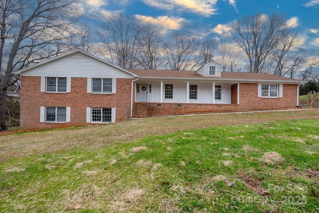 view of front of home featuring crawl space, brick siding, covered porch, and a front yard