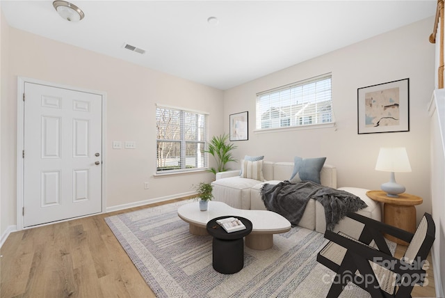 living room featuring light wood finished floors, visible vents, and baseboards