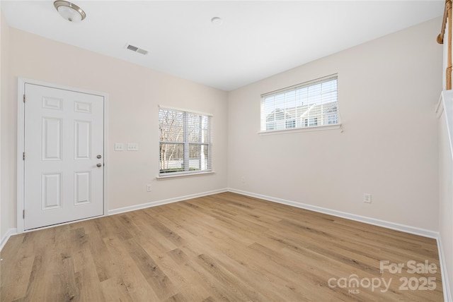 unfurnished room featuring light wood-style flooring, visible vents, and baseboards