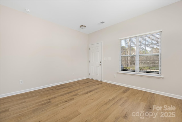 unfurnished room with visible vents, baseboards, and wood finished floors