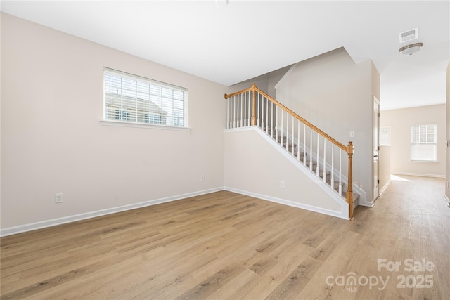 spare room featuring light wood-style flooring, stairway, visible vents, and baseboards