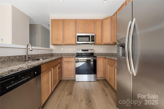 kitchen with light wood-style flooring, appliances with stainless steel finishes, stone counters, a sink, and recessed lighting