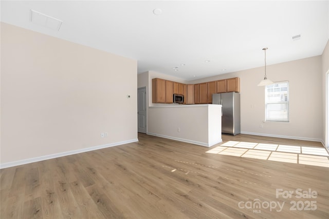 unfurnished living room with light wood-style floors, visible vents, and baseboards