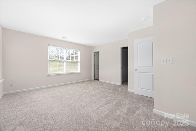 unfurnished room with baseboards and light colored carpet