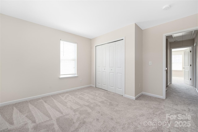 unfurnished bedroom with carpet floors, multiple windows, attic access, and baseboards