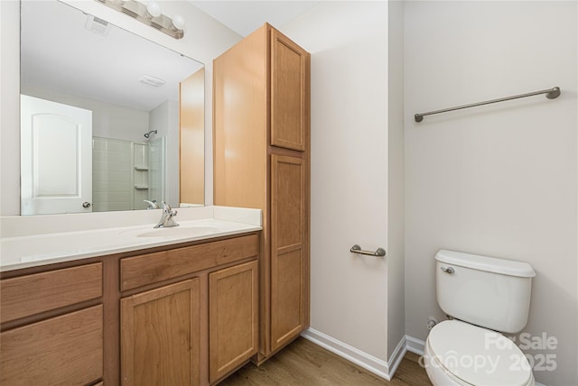 bathroom with a shower, visible vents, toilet, vanity, and wood finished floors