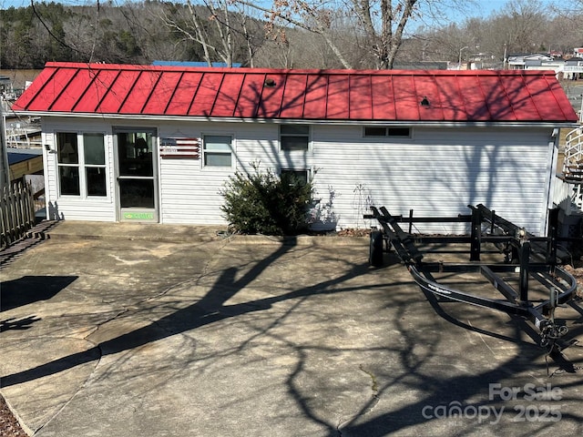 back of house with a standing seam roof, metal roof, and a patio