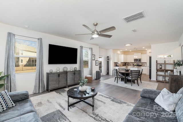 living room featuring a healthy amount of sunlight, visible vents, ceiling fan, and light wood-style flooring