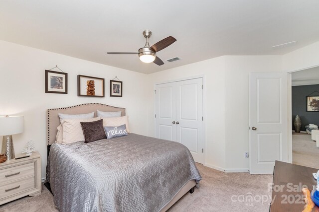 bedroom with a closet, visible vents, light carpet, ceiling fan, and baseboards