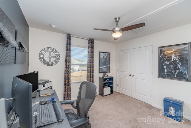 carpeted office space with a ceiling fan and baseboards