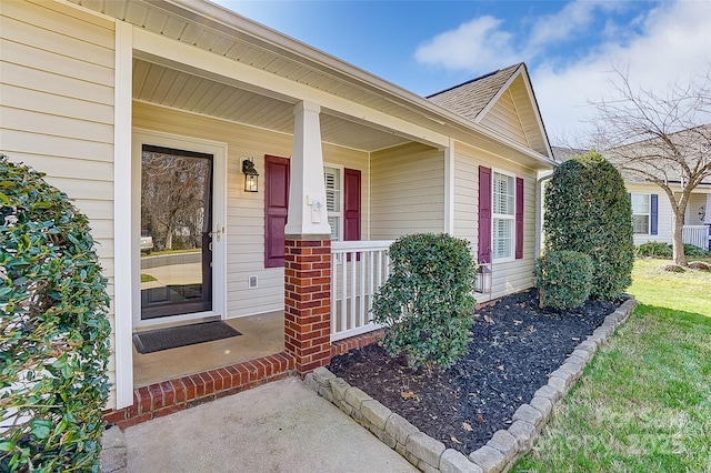 property entrance featuring covered porch and a shingled roof