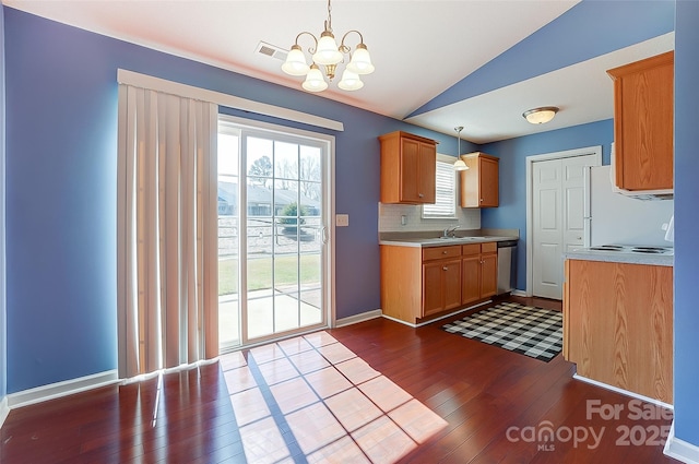 kitchen with lofted ceiling, dark wood-type flooring, visible vents, light countertops, and stainless steel dishwasher