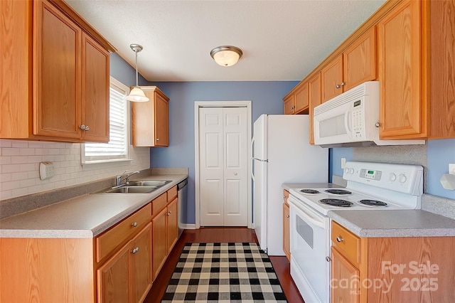 kitchen with white appliances, a sink, hanging light fixtures, light countertops, and backsplash