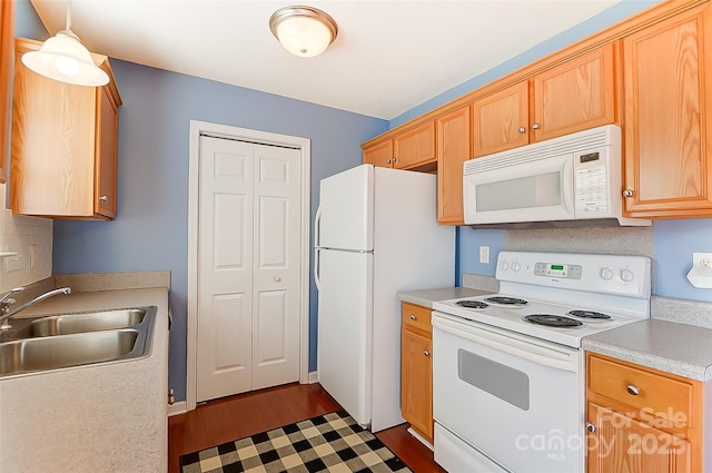 kitchen with dark wood-style floors, light countertops, white appliances, and a sink